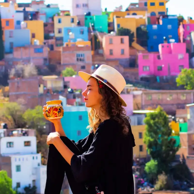 Colorful houses in Guanajuato, Mexico with woman drinking coffee in foreground