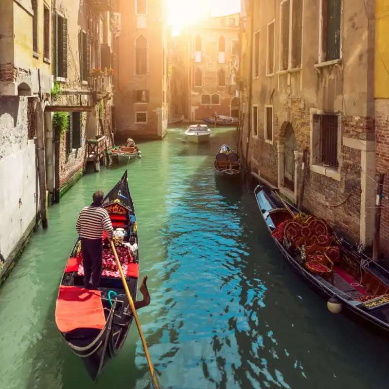 a man punting a gondola down a canal street in venice italy